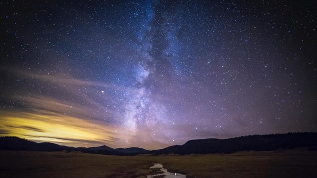 The Milky Way and a night sky bursting with stars over a small stream.