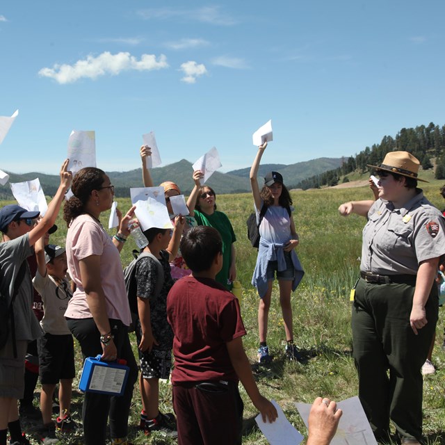 A park ranger conducts an outdoor program with a large group of students.
