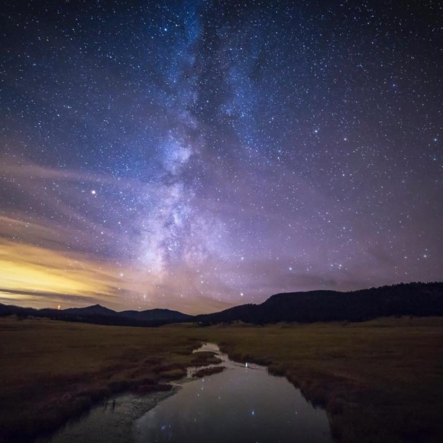 The Milky Way and a night sky bursting with stars over a small stream.
