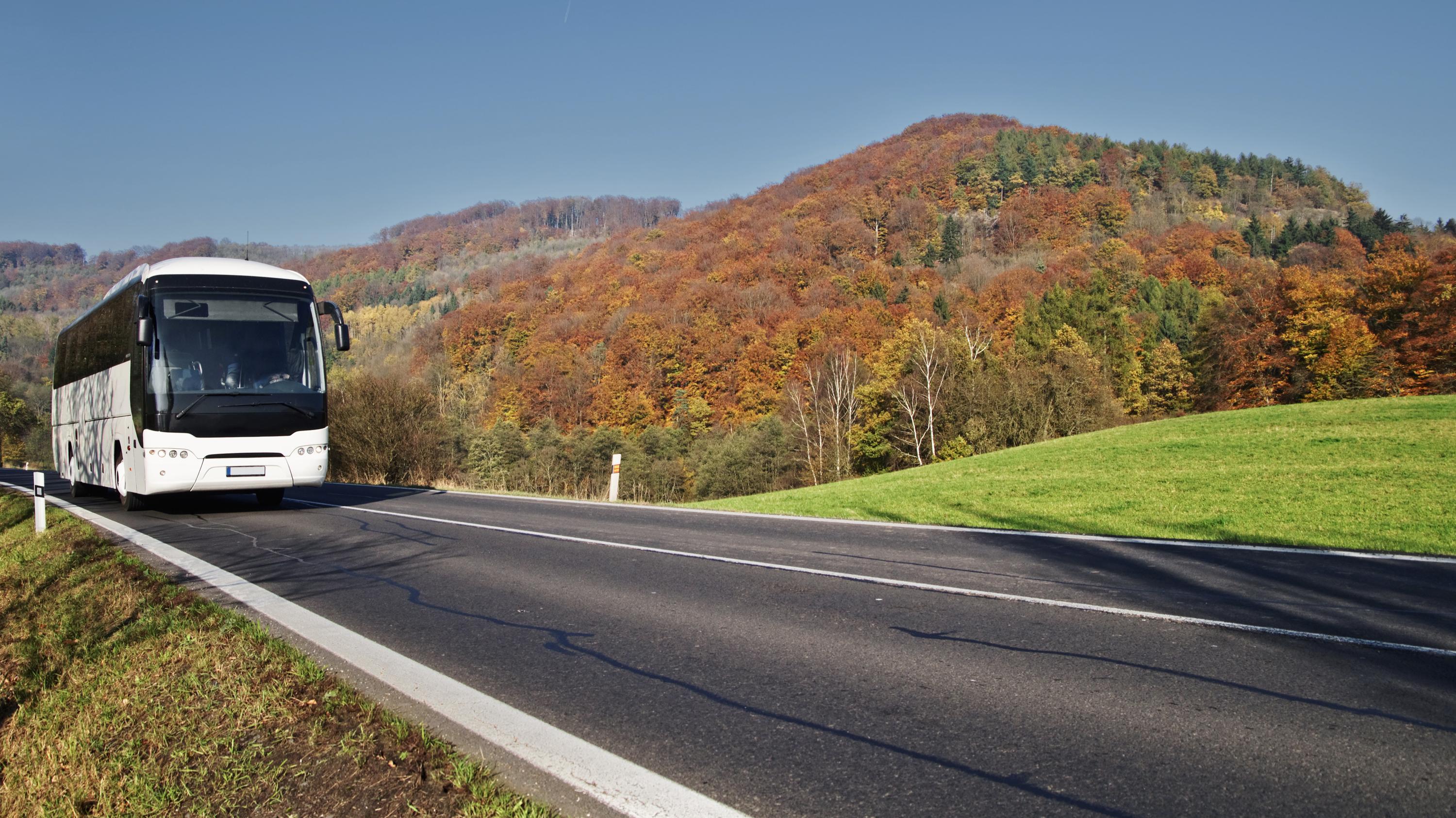 A bus driving along a highway in a hilly landscape.