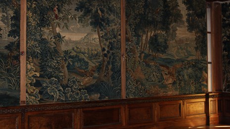 A room with paneled walls and large tapestries.