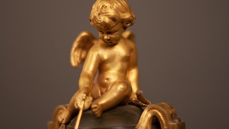 A gilt cherub holding an arrow.