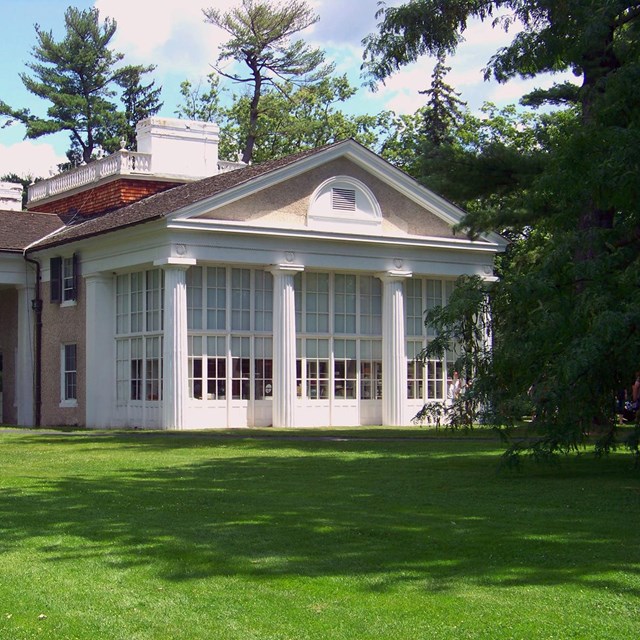 A classical building with pedimented portico and captain's walk on the roof.