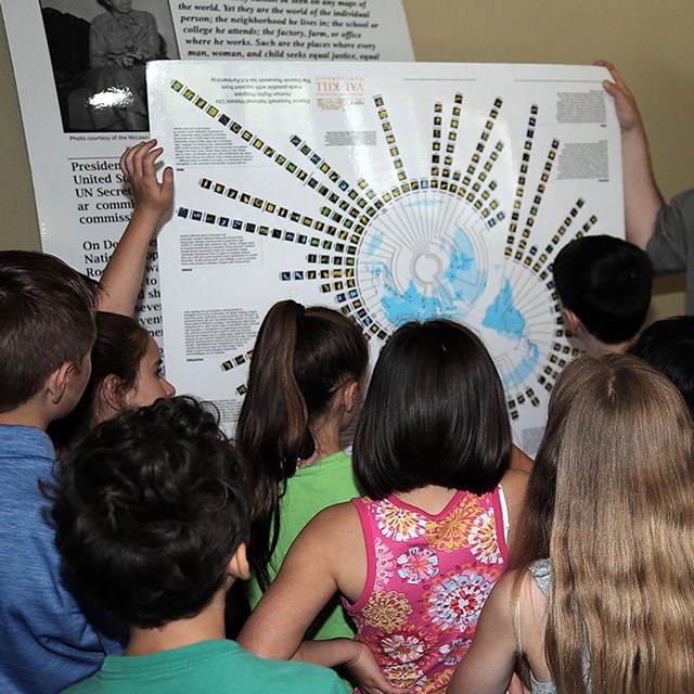 A group of students looking at a diagram on a large piece of paper.