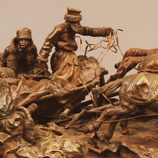 A bronze sculpture of a group of people riding a horse-drawn sleigh.