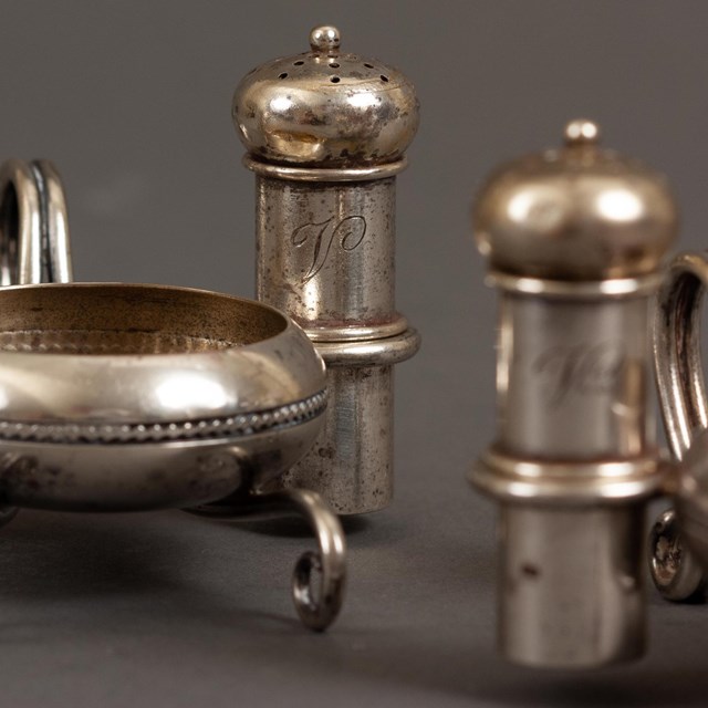 A pair of individual silver salt cellars and casters monogrammed with a V.