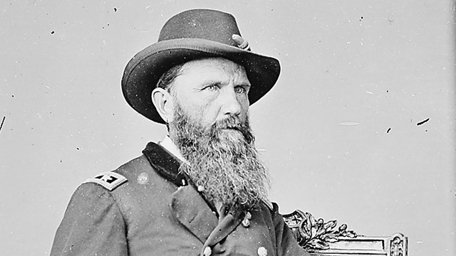 General Blair in military uniform sitting in a chair holding a chair between his fingers.