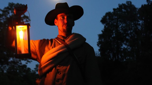 A soldier hold a lantern at night.