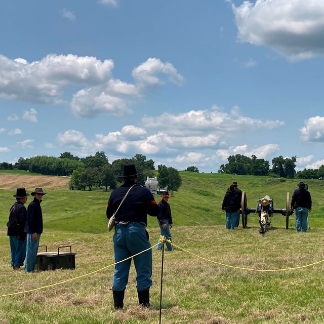 Volunteers in Civil War uniforms standing around a cannon during Fourth of July.