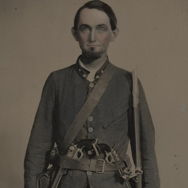 A Confederate soldier from South Carolina with two pistols tucked in his belt and musket on his left