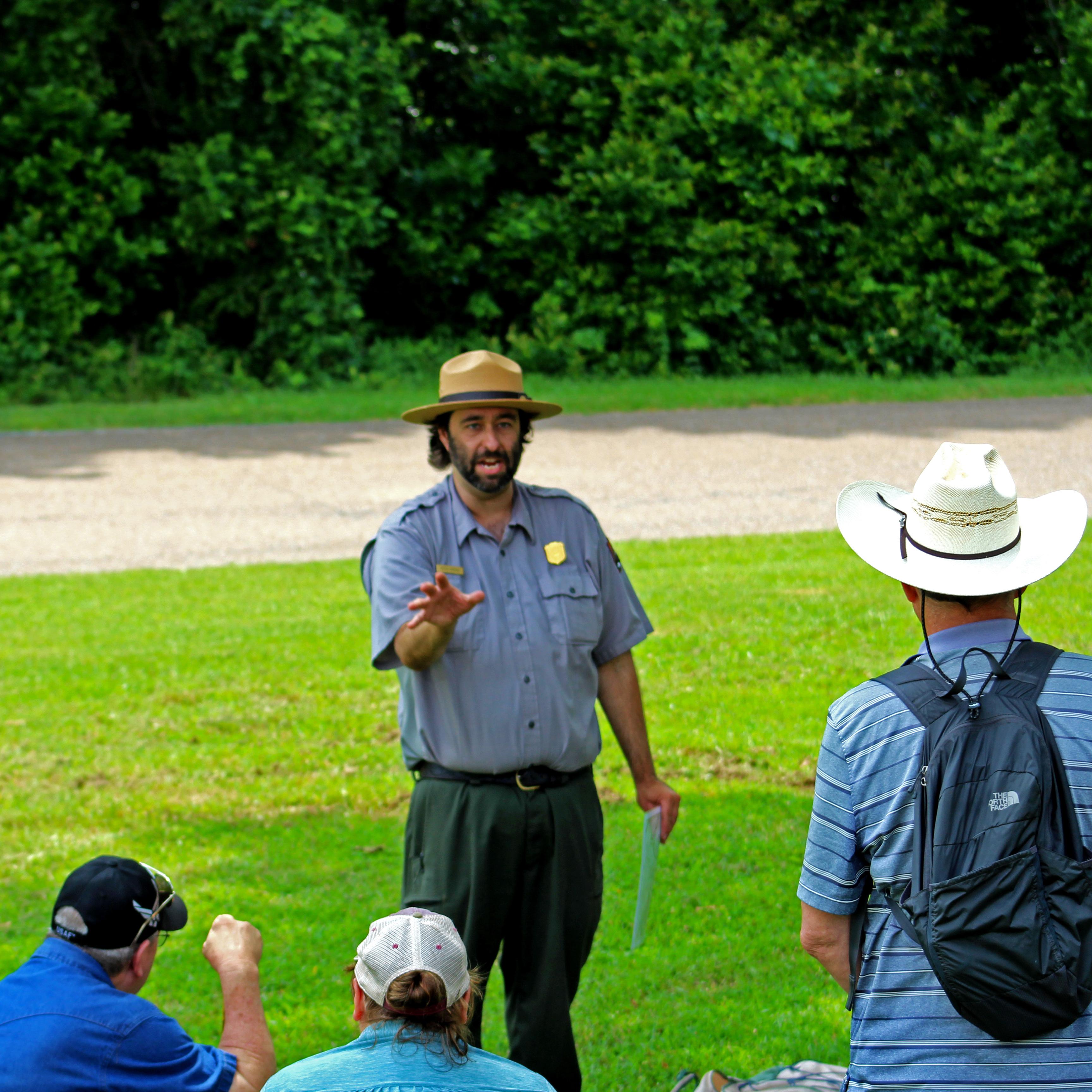 Park Ranger talks to group of visitors in the grass
