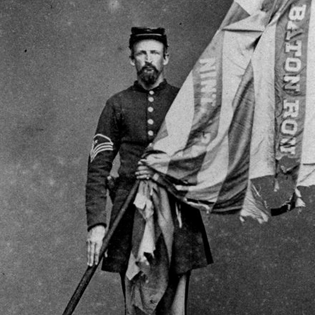 A Union soldier holding the American flag across his body.