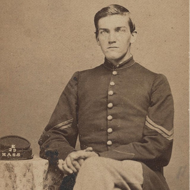 A Union soldier sitting with his cap on the table next to him.