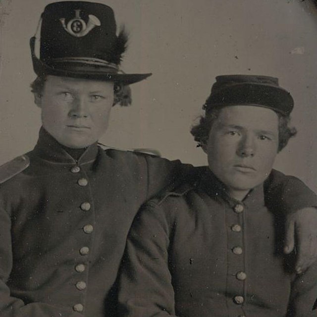 Two Union soldiers sitting, one with his arm around the other's shoulders.