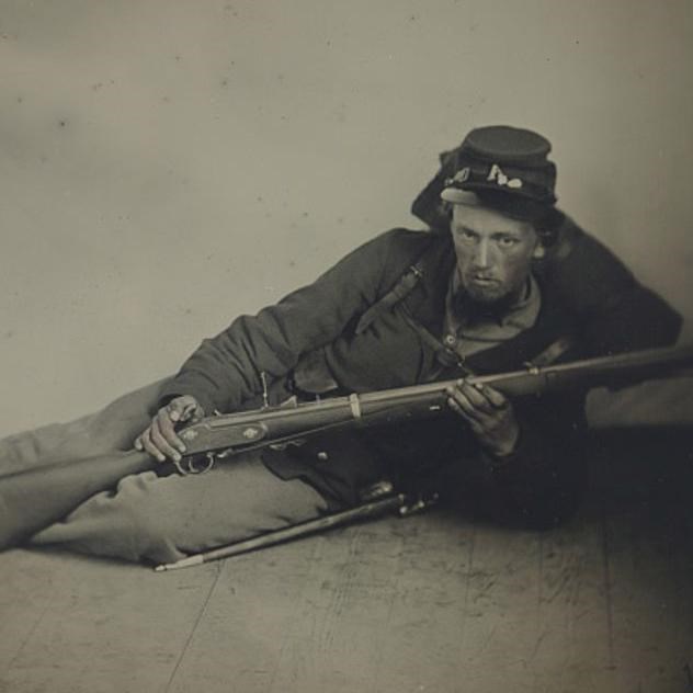 A Union soldier laying on the floor showing his cocked musket.