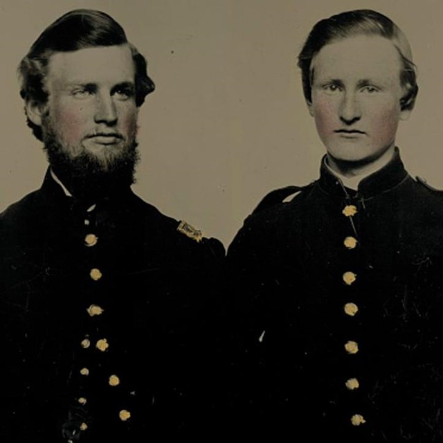Two brothers in the union army sitting for their picture with one looking at the camera.