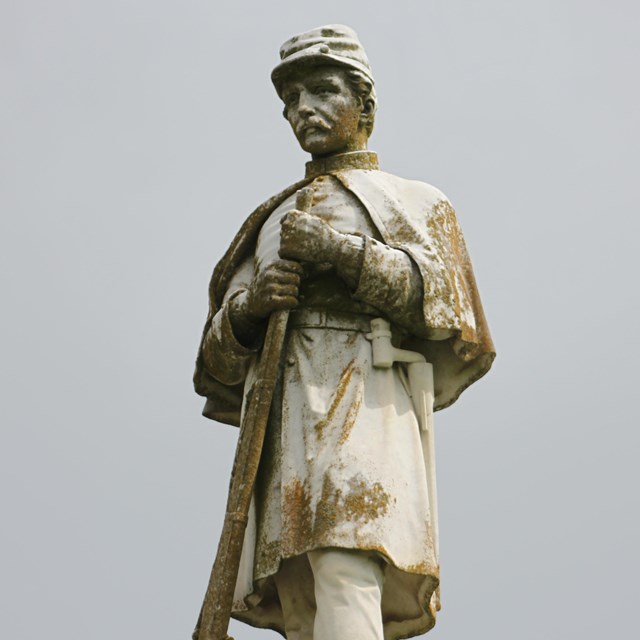 A large white statue of Confederate soldier in uniform 