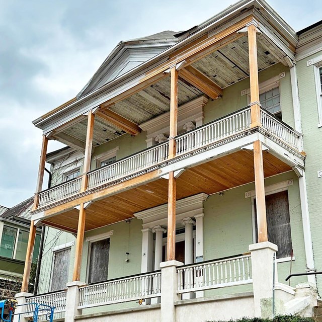 A two story home with a upper and lower story porches under renovation