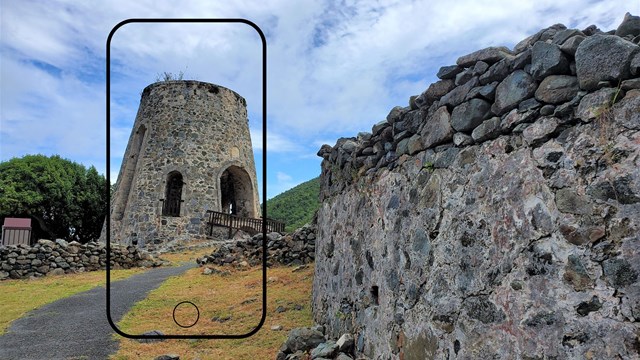 Phone outline around windmill base made of colorful masonry with masonry wall in front