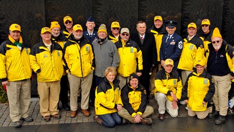 Volunteers pose for a photo in front of the Vietnam Veterans Memorial