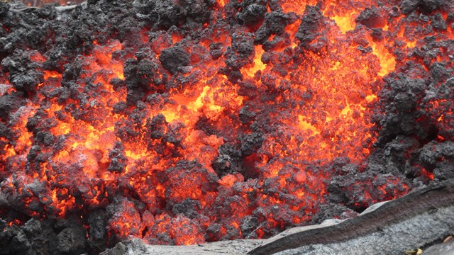 Photo of a molten lava with a partial crust of hardened lava rock.
