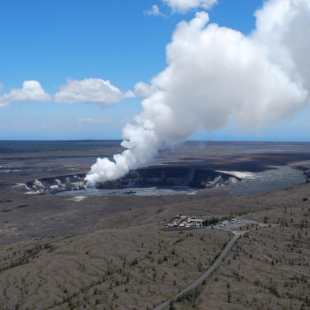 photo of a mountain top caldera with a plume of steam rising into a clear blue sky.