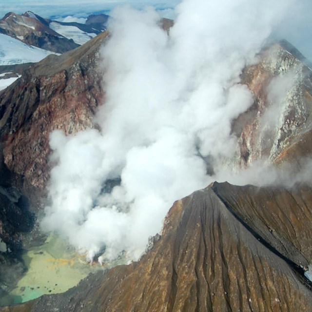 aerial view into steaming volcanic crater