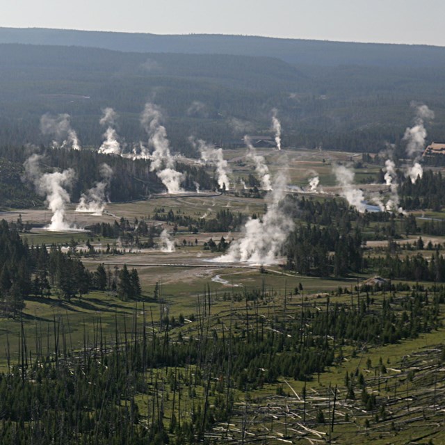 mountain valley with numerous steam plumes rising into the air