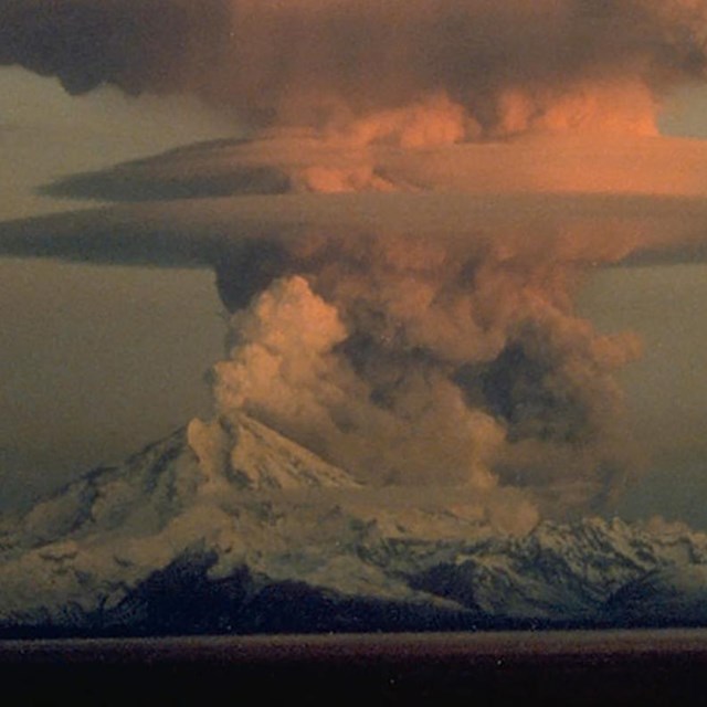 erupting volcanic mountain with ash cloud above