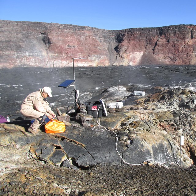 Photo of a person in the field investigating a volcanic crater.