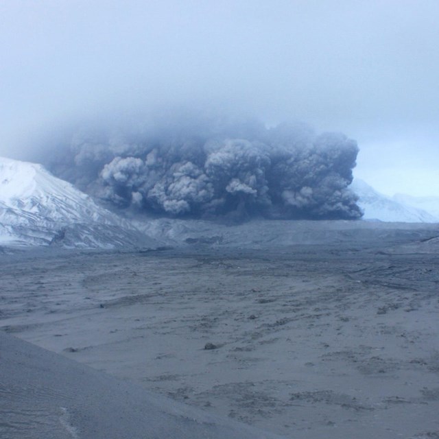 Photo of a cloud of ash and dust moving down a mountain valley.