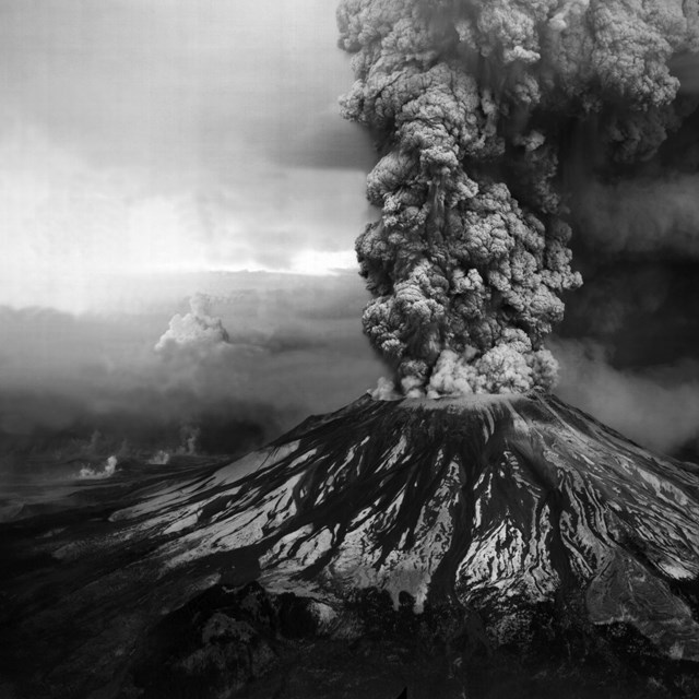 erupting volcanic mountain with ash cloud above