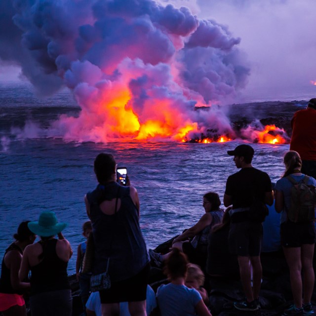 photo of people watching lava flow into the ocean 