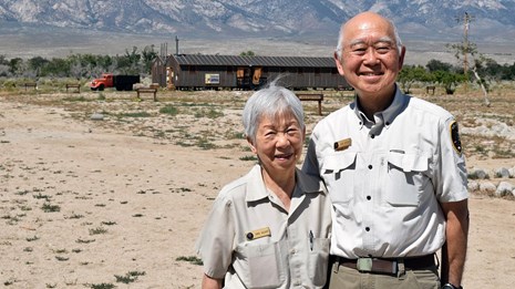 Two volunteers standing together on a desert landscape.