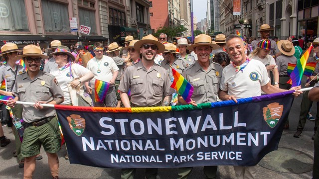 A group of people in park ranger and volunteer uniforms walking in a parade.