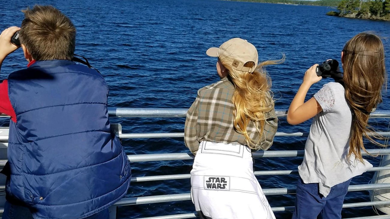 Image of 3 kids looking over the water from a boat