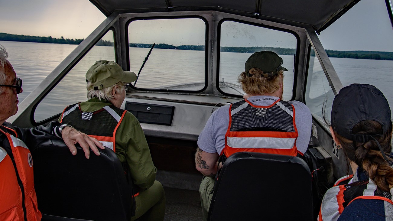 Image of 4 adults with PFDs in a boat on the water