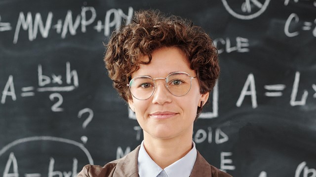 Image of a lady standing in front of a blackboard