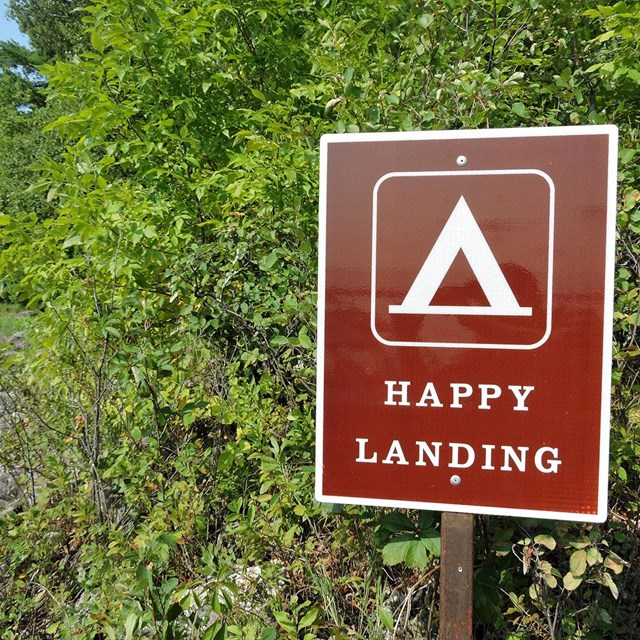 A brown sign with a tent symbol labeled 