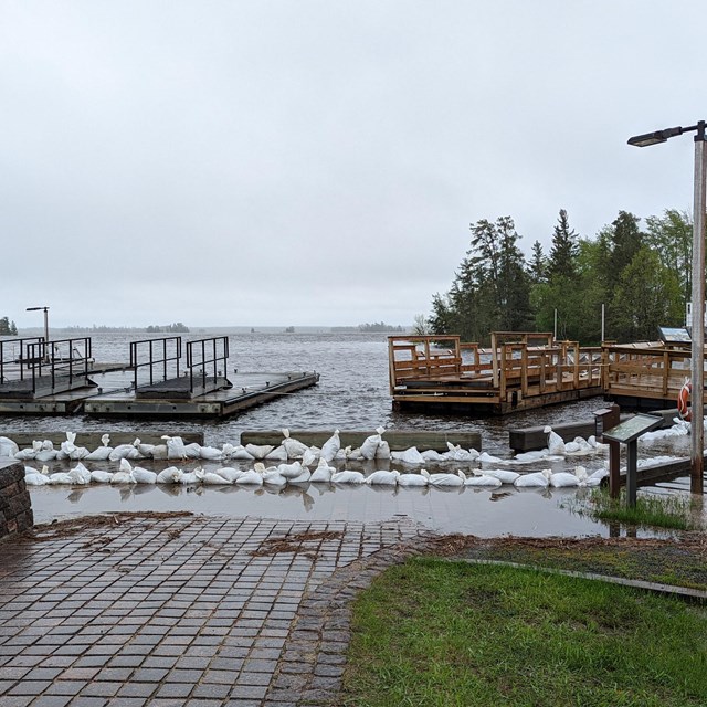 High water covering walkway, in front of lake with wooden platforms floating in the water