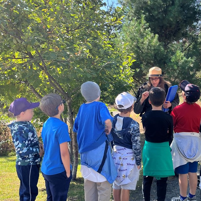 School children with ranger near trees and plants