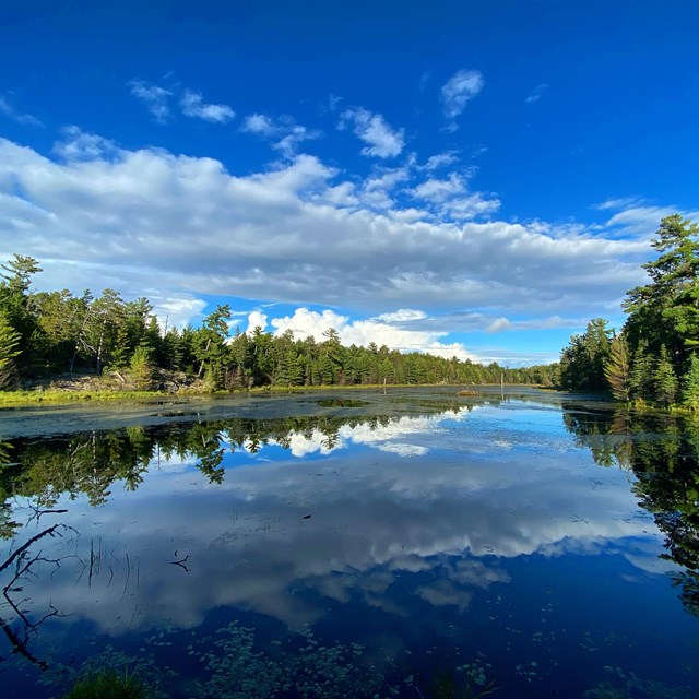 A bright blue lake with the clouds reflected in the water. 