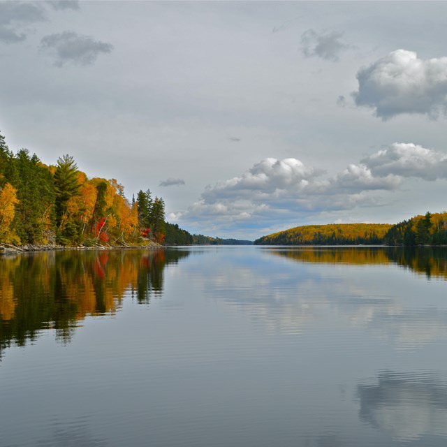 Trees with yellow, red, and orange leaves surround a lake on either side.
