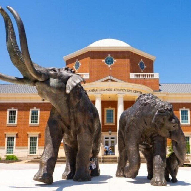 Mammoth statue in front of brick two-story bulding