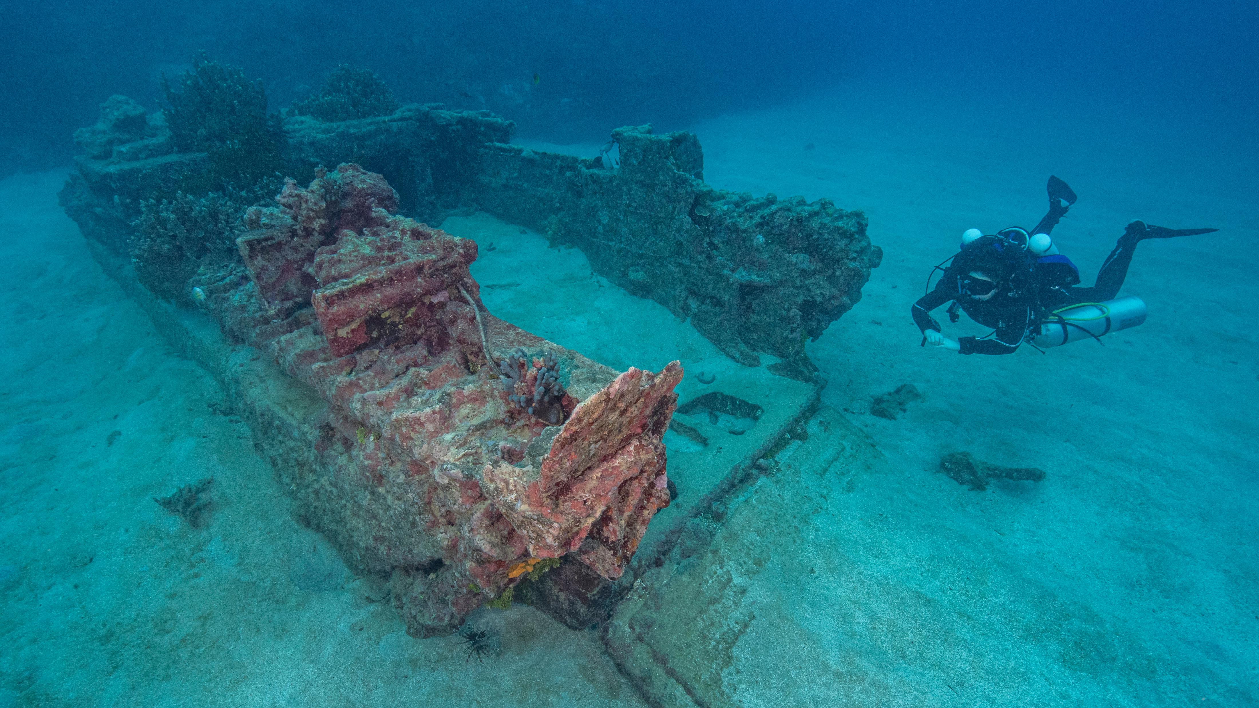 A woman scuba diving next to the wreck of an Amtrac amphibious tractor