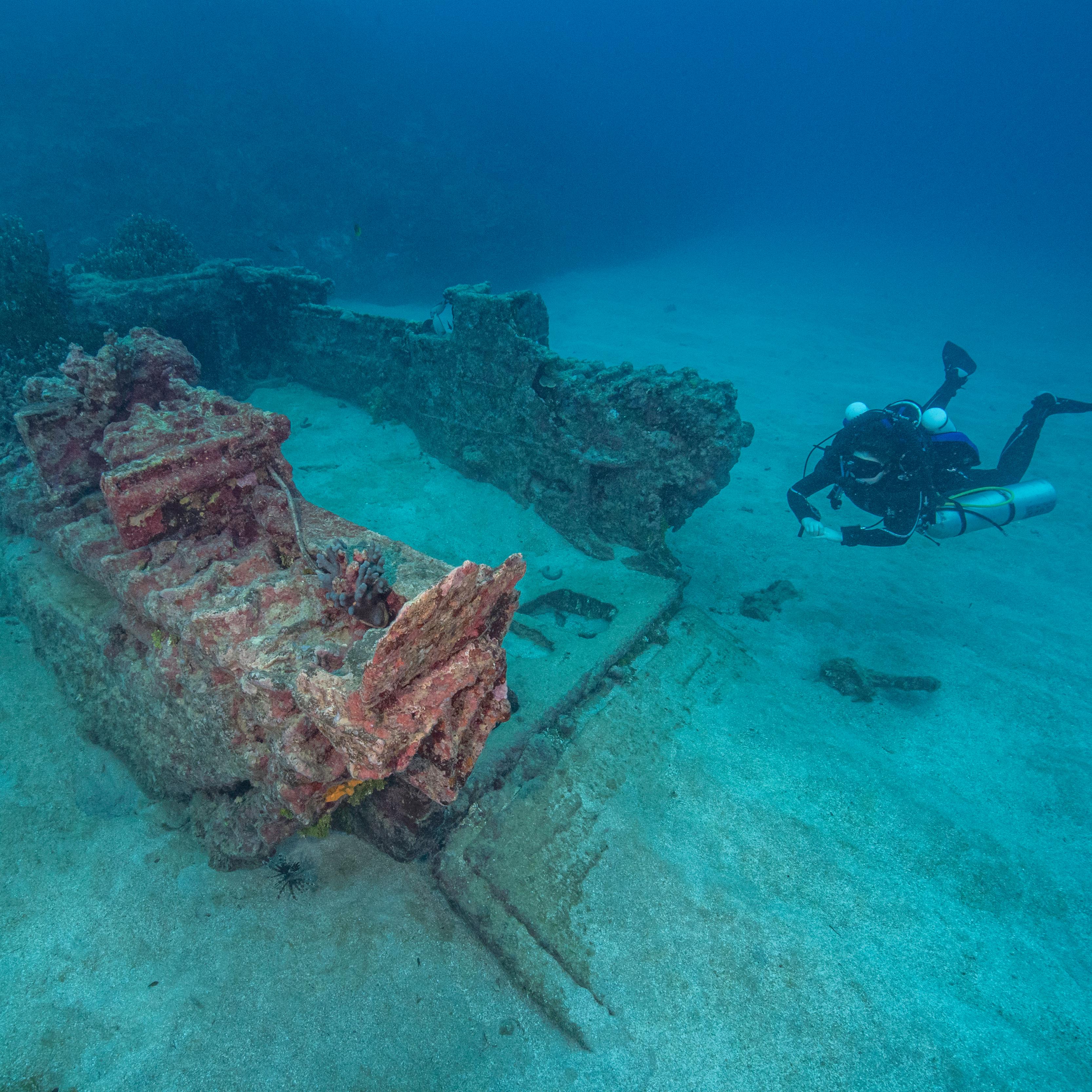 A woman scuba diving next to the wreck of an Amtrac amphibious tractor