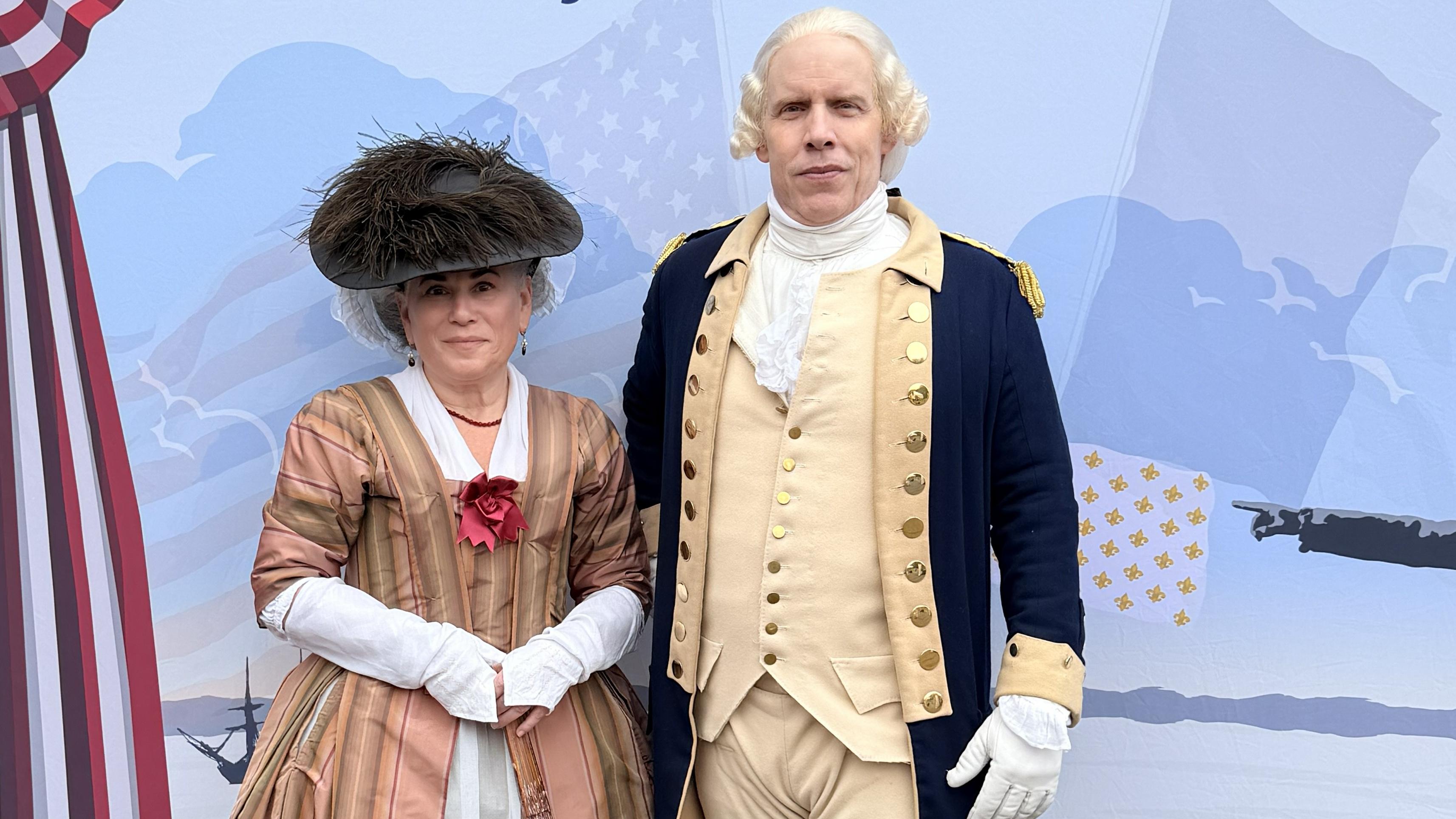 Living history interpreters portraying George and Martha Washington stand beside a trail banner.