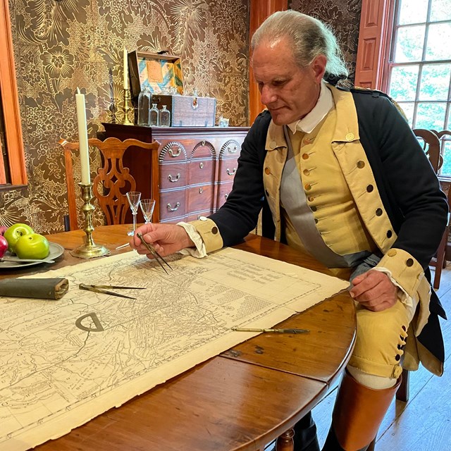 Washington sitting down looking over maps 
