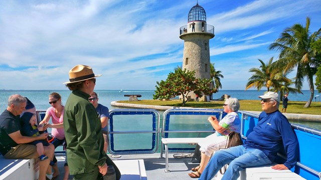 Ranger leading a boat tour with lighthouse in background