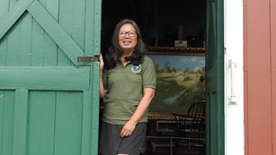 A volunteer standing in an open doorway with a painting behind them.